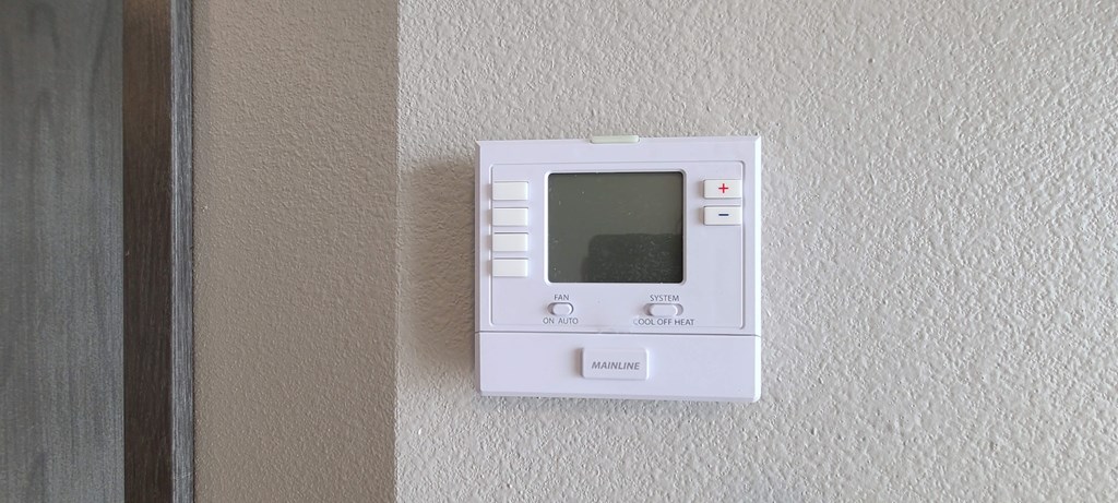 a white thermostat on a wall next to a door