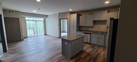 an empty kitchen and living room with a door to a balcony