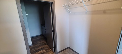 a walk in closet with a white wall and a closet door open