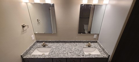 a bathroom with two sinks and two mirrors