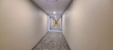 a long hallway with white walls and a patterned carpet on the floor