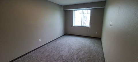 an empty room with a window and carpet