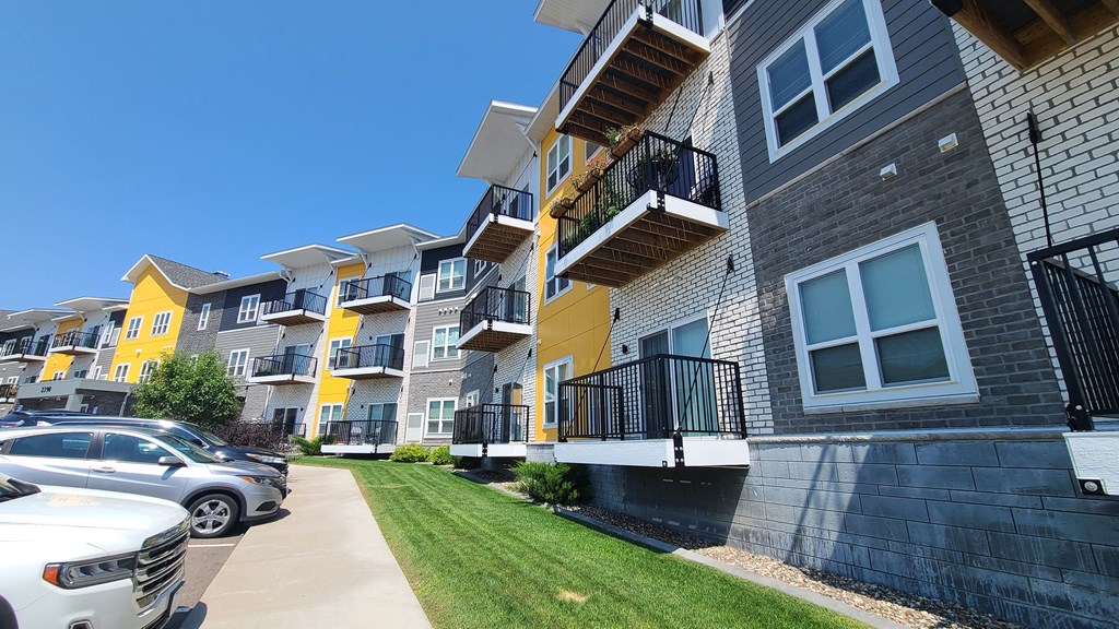a row of apartments with balconies and cars parked in front