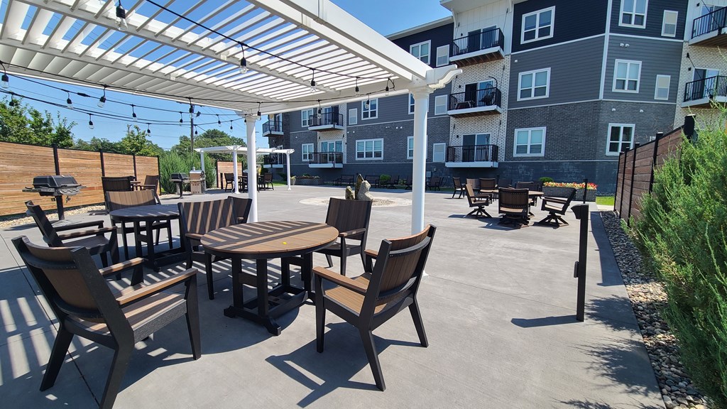 an outdoor patio with tables and chairs under a white canopy