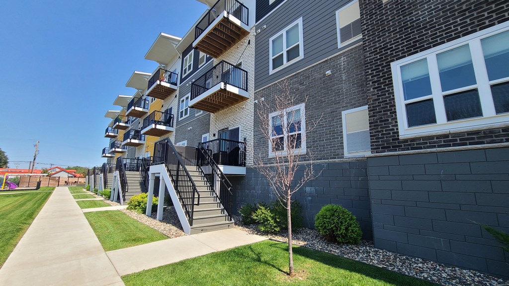 an exterior view of an apartment building with grass and a sidewalk
