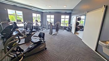 a gym with cardio equipment and windows in a building