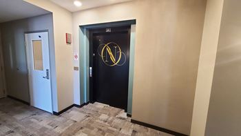 a black door with a gold logo on it in a hallway