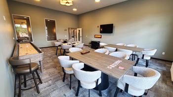 a game room with tables and chairs and a shuffleboard