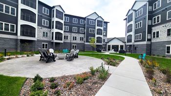 an outdoor area with chairs and a table in front of an apartment building