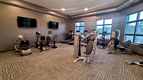 a gym with treadmills and other exercise equipment in a building with large windows