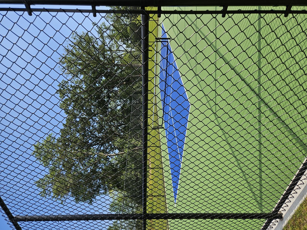 A blue and yellow umbrella is attached to a black fence.