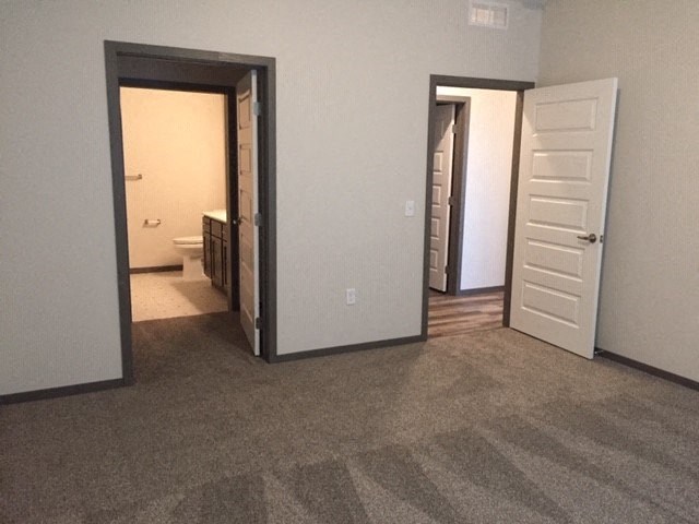 an empty living room with a door open to a bathroom