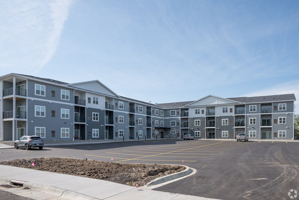 an exterior view of an apartment building with a parking lot