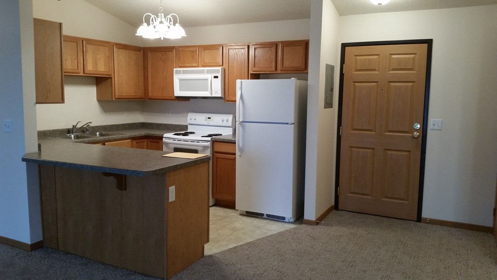 A kitchen with a white refrigerator and a white microwave above the stove.