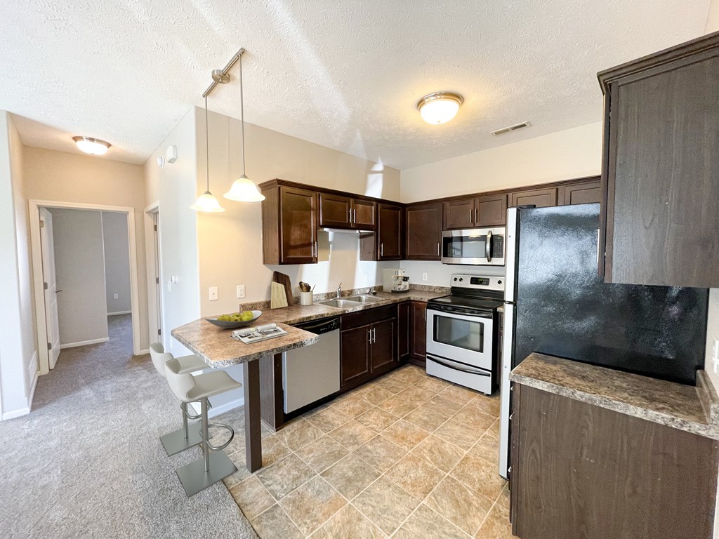a kitchen with stainless steel appliances and a bar with a counter top