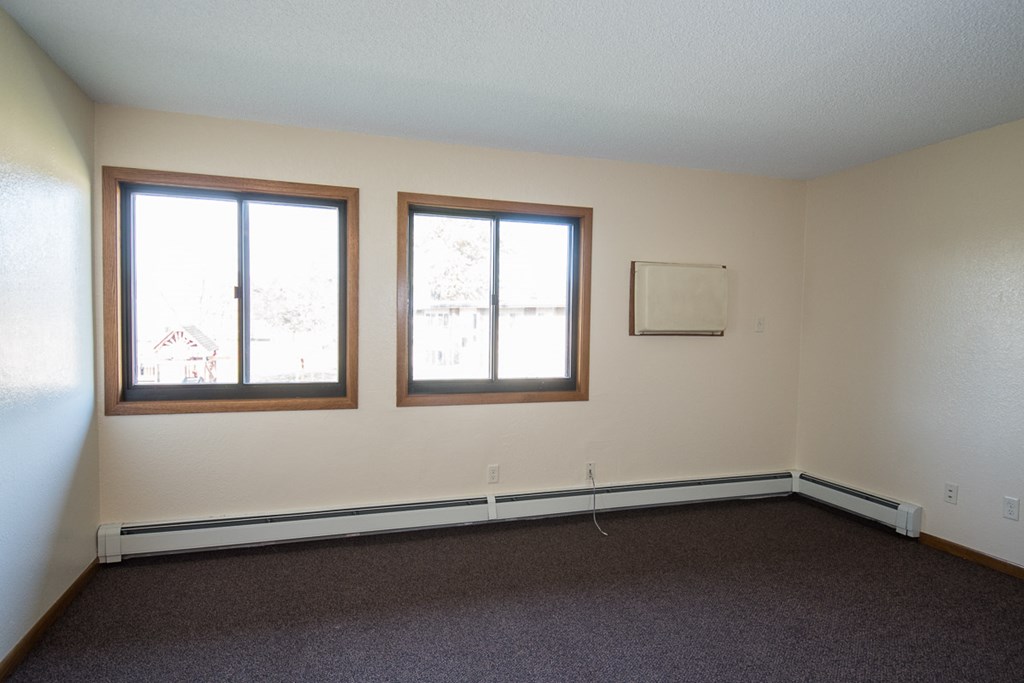 A room with two windows and a carpeted floor.