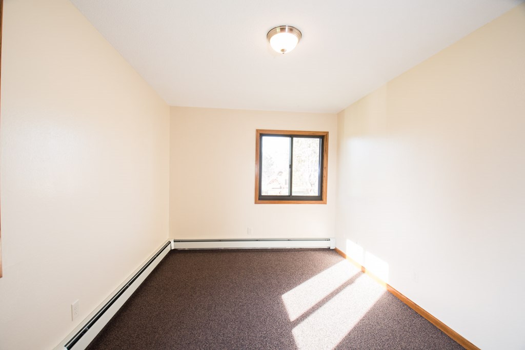 A room with a window and carpeted floor.