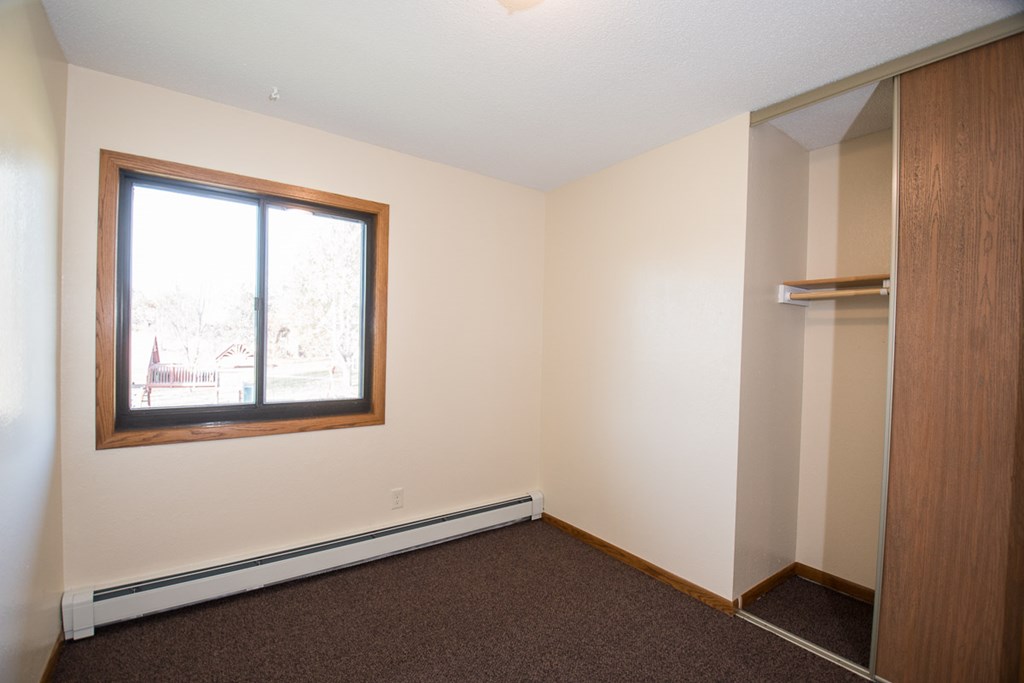 A room with a brown carpet and a window.