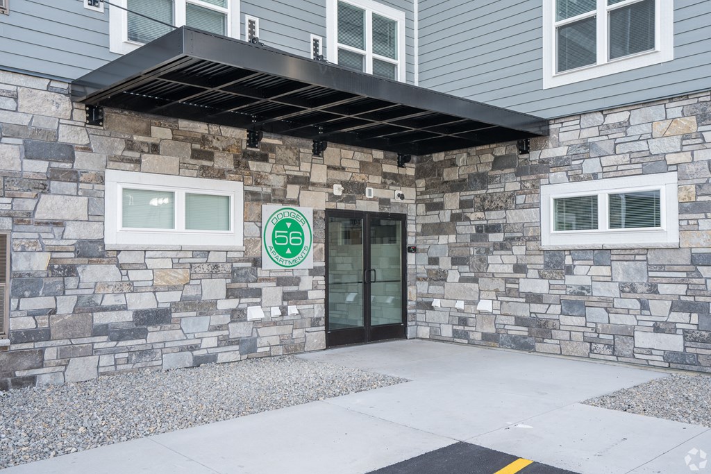 a stone building with a glass door and a green sign on it