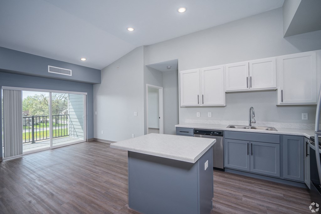 a kitchen with a large island and a door to a balcony