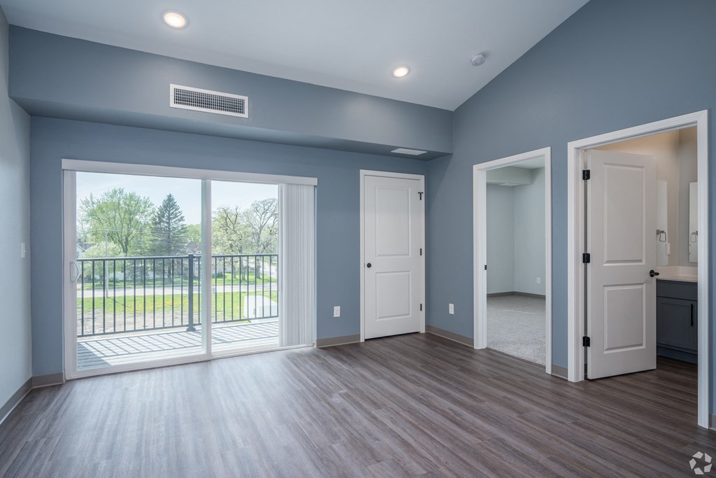 an empty living room with doors and a balcony