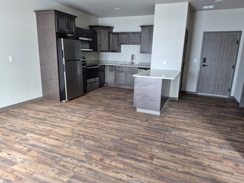 A kitchen with a black refrigerator and wooden floors.