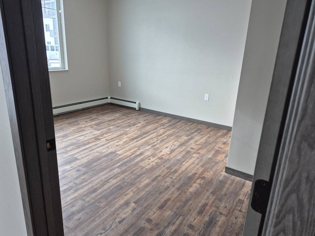 A room with wooden flooring and a window.