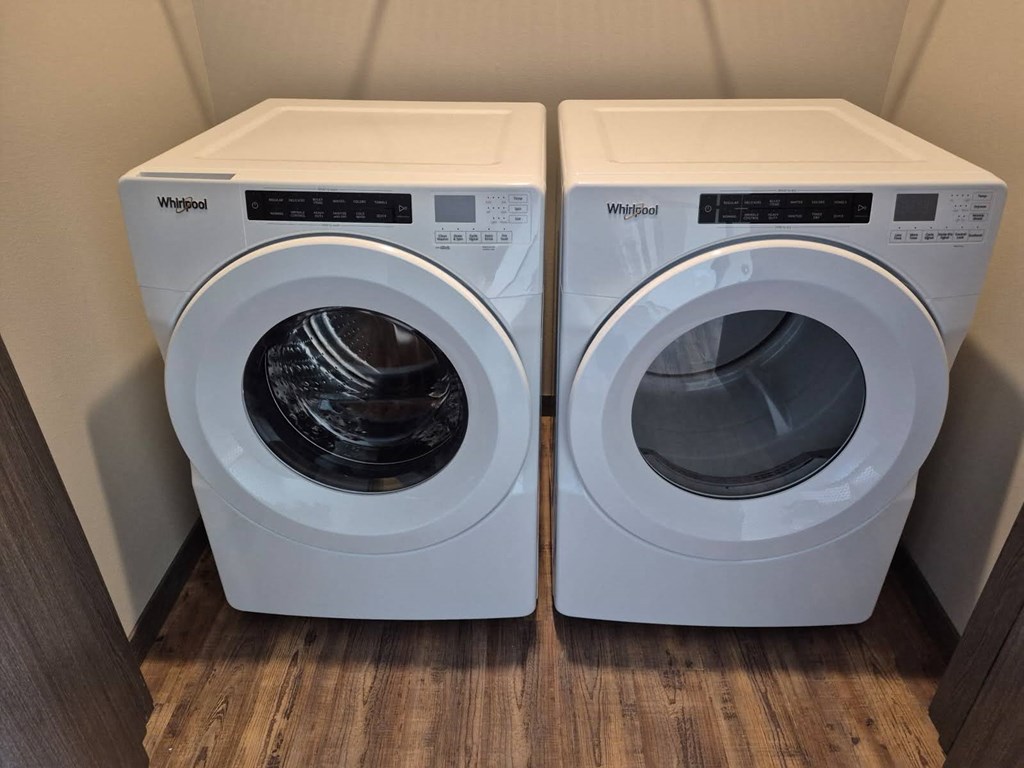 Two white Whirlpool washing machines in a small room.
