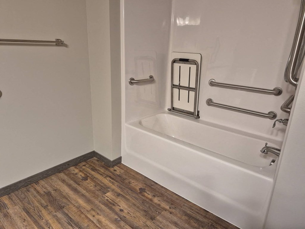 A white bathtub with a shower head and hand held shower.