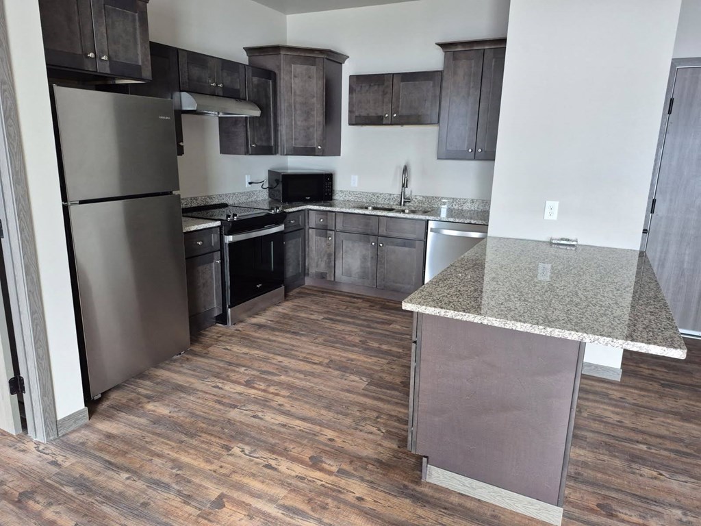A kitchen with a refrigerator, oven, and microwave.