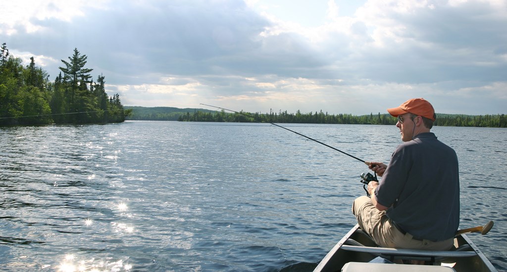 a man fishing in a boat on a lake