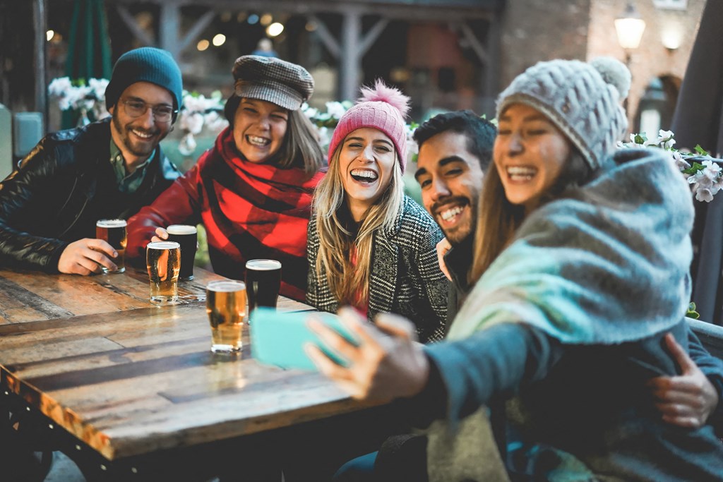 group of people sitting at a table drinking beer and laughing