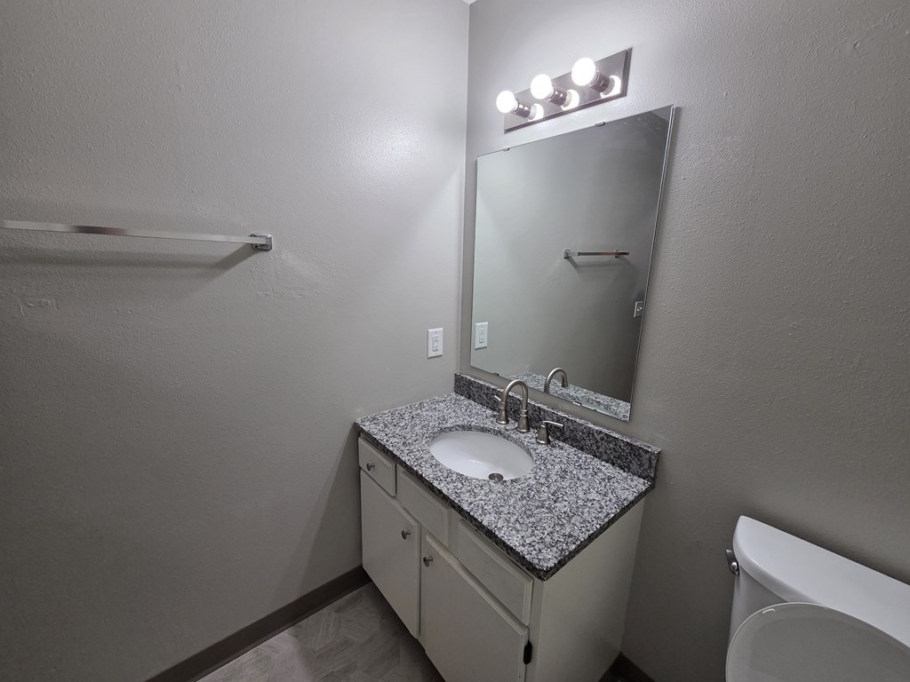 A bathroom with a sink, mirror, and towel rack.