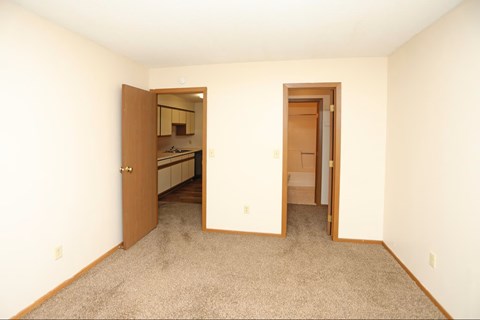 A room with a carpeted floor and two open doors.