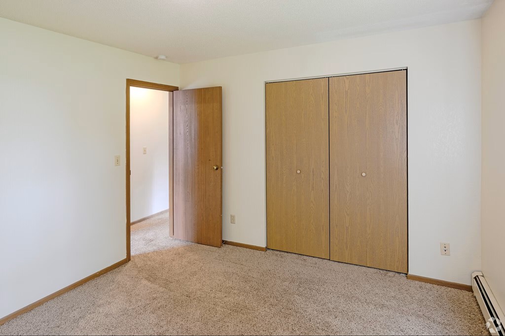 A room with a carpeted floor and two wooden doors.