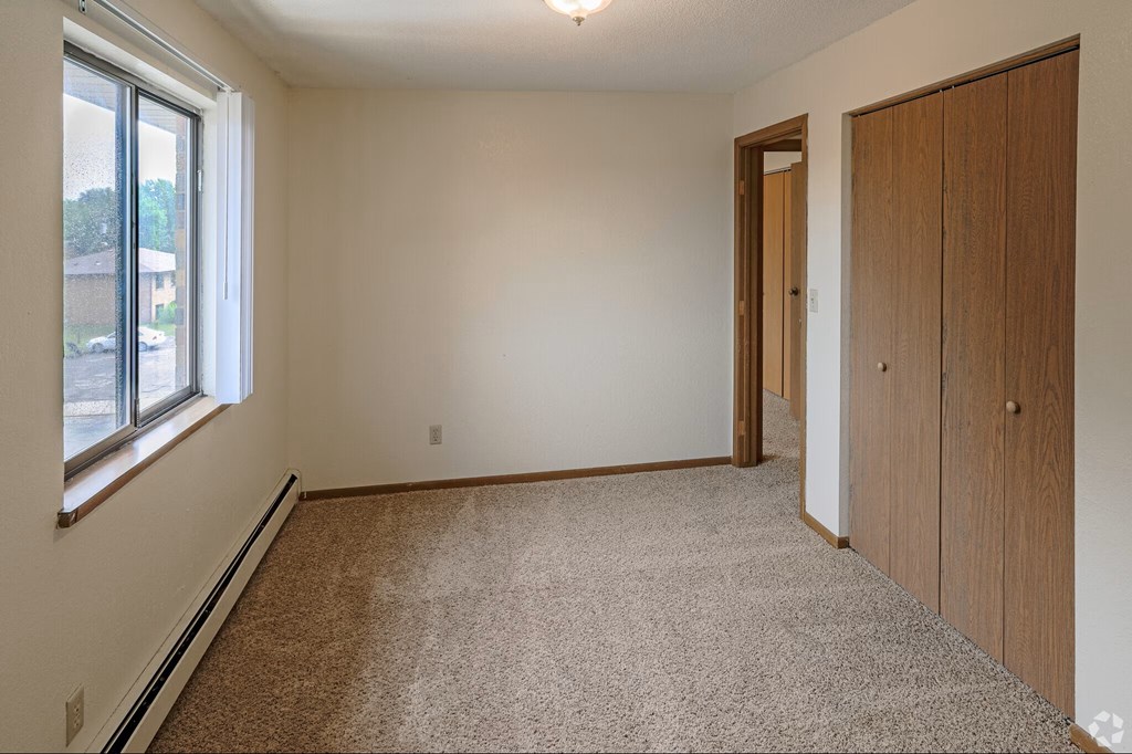 A room with a carpeted floor, a door, and a window.
