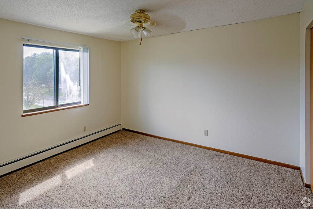 A room with a carpeted floor and a ceiling fan.