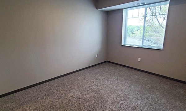 an empty room with a window and carpet