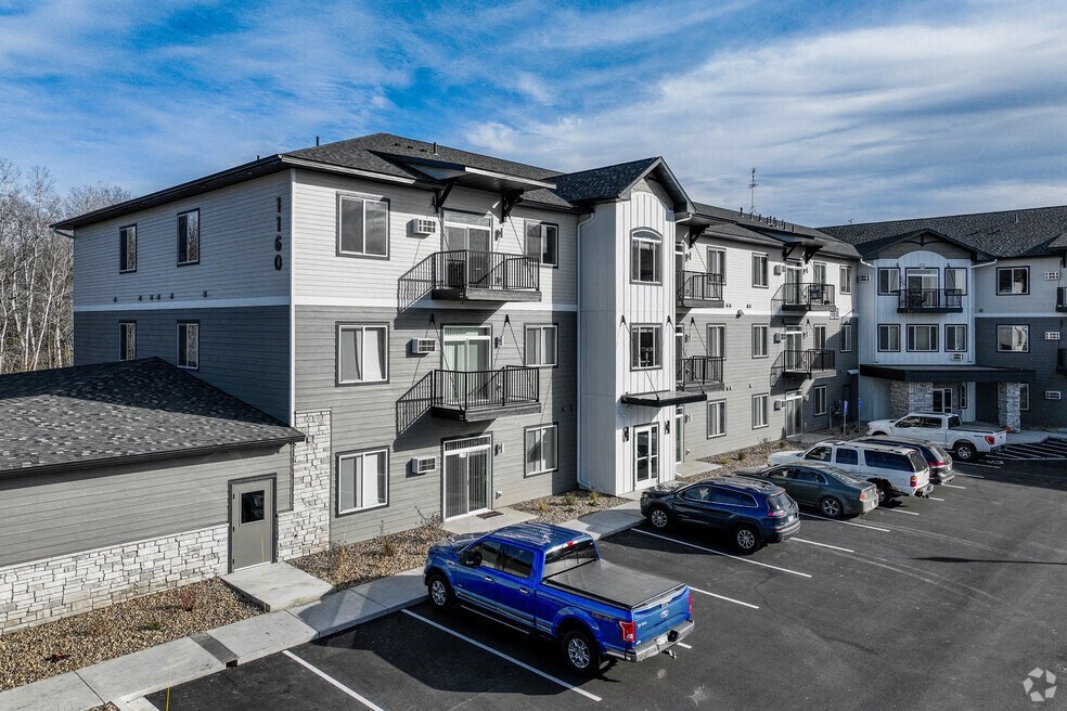 a rendering of a white and black apartment building with cars parked in front