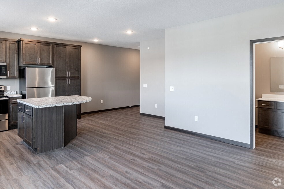 an open kitchen and living room with wood flooring and stainless steel appliances