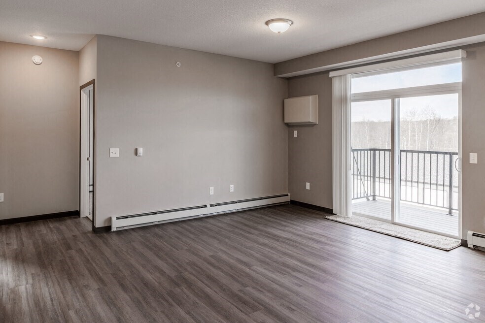 the living room of a new home with a large window and wood flooring