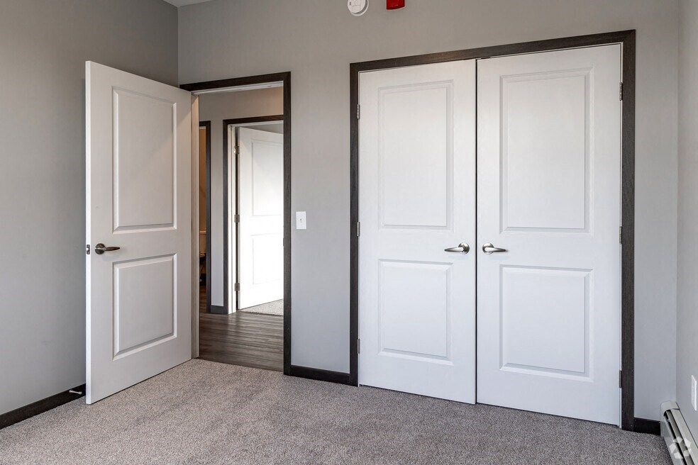 an empty room with white doors and a door to a hallway