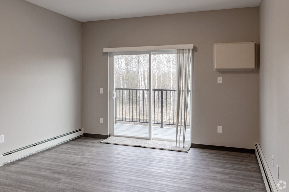 an empty living room with a sliding glass door to a balcony