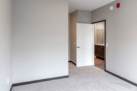 an empty bedroom with a door open to a bathroom