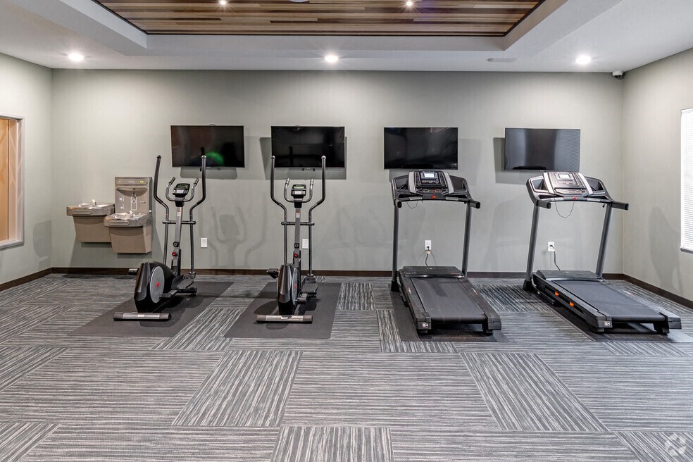 a gym with treadmills and televisions on the wall