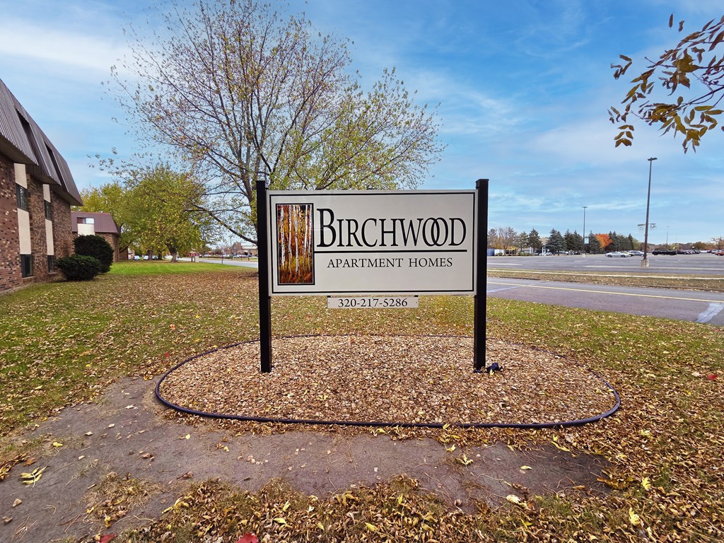 A sign for Birchwood Apartment Homes stands in a grassy area.