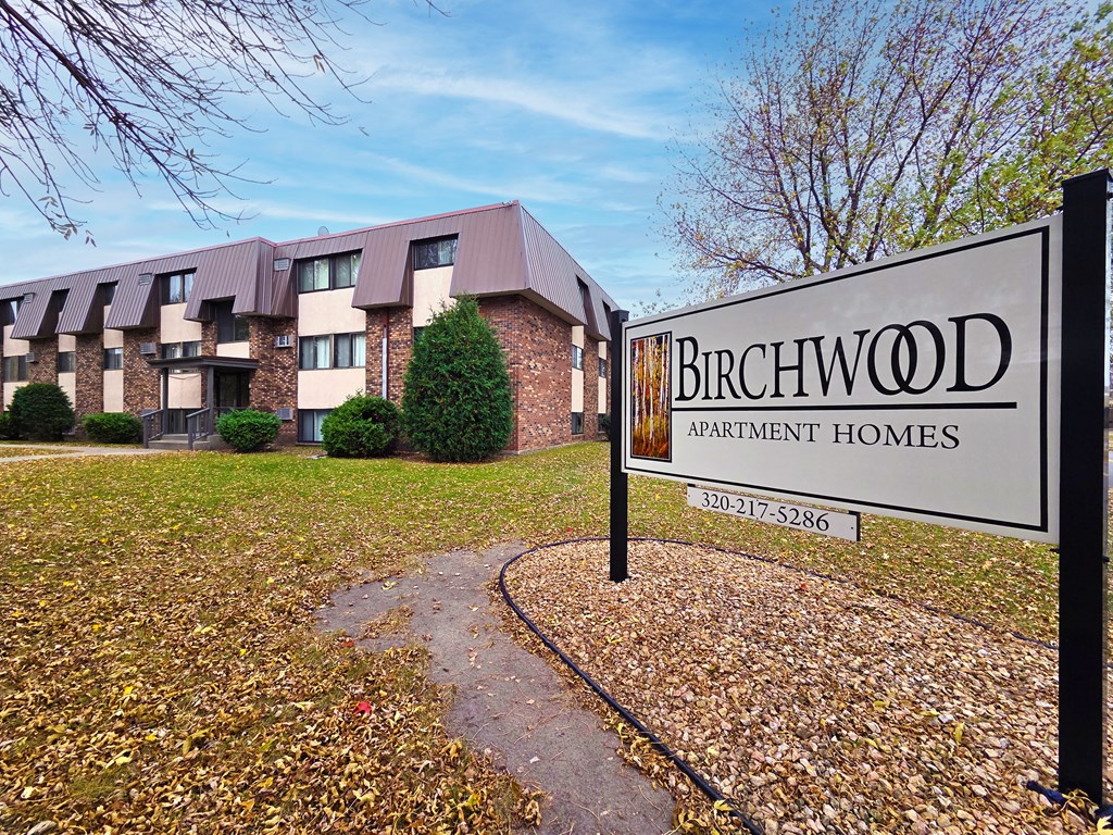 A sign for Birchwood Apartment Homes stands in front of a building.