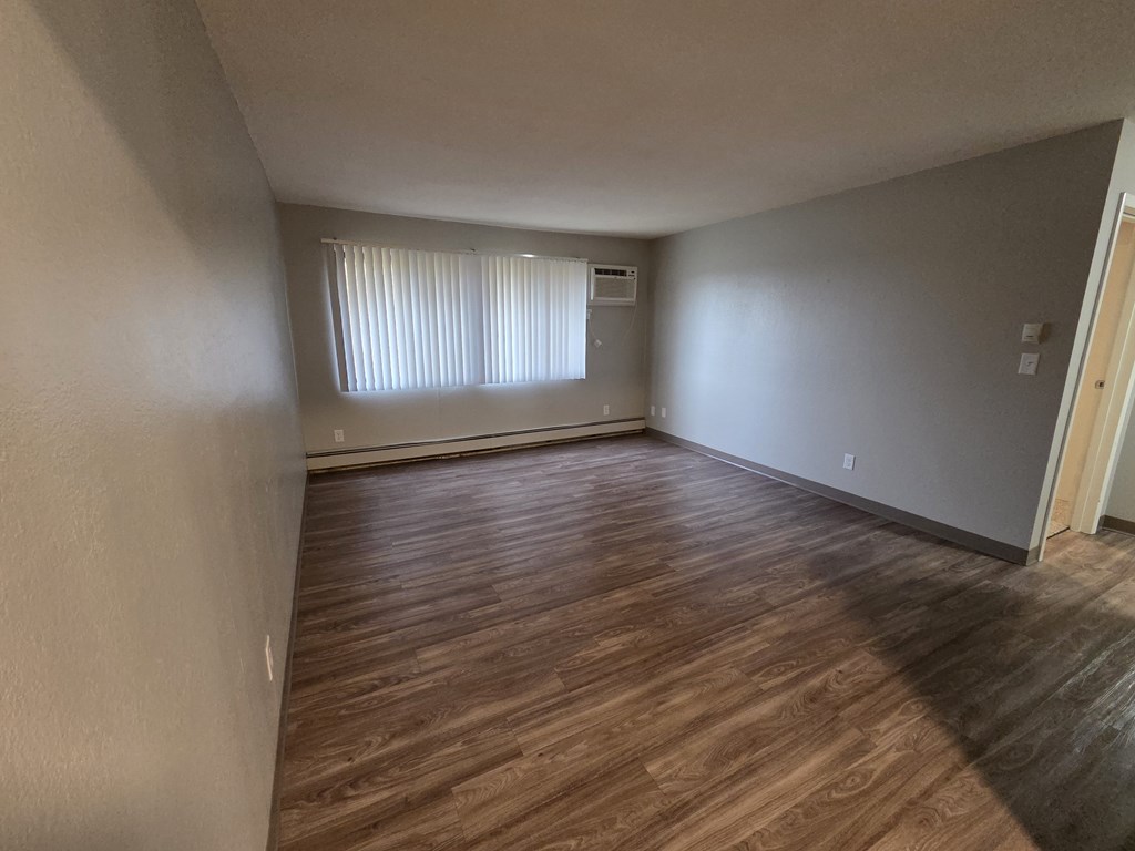 A room with wooden flooring and a window with blinds.
