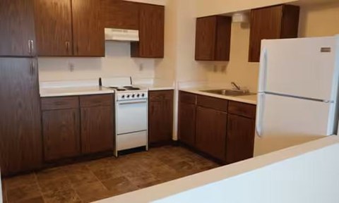A kitchen with brown cabinets and a white refrigerator.