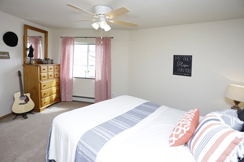 A bedroom with a bed, dresser, and guitar.